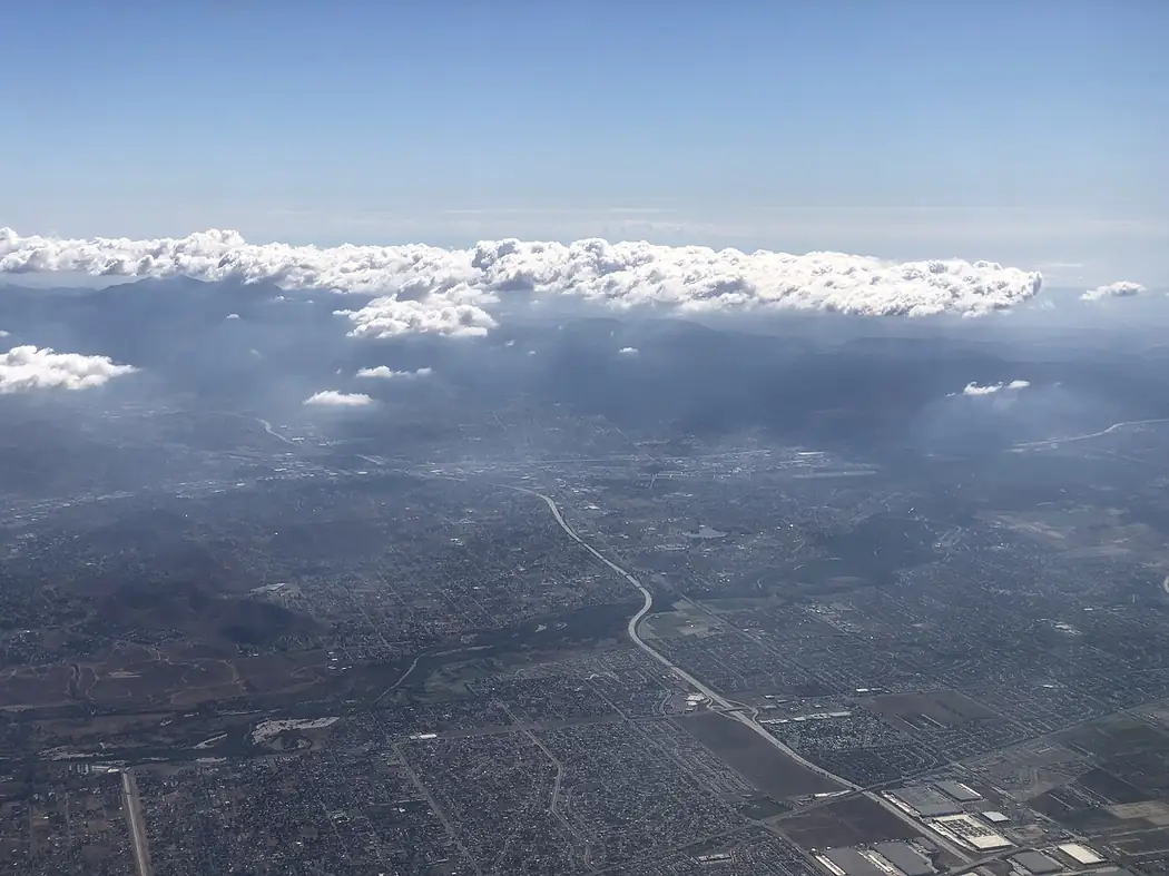 Aerial view southwest along Interstate 15 toward Corona in western Riverside County, California, with clouds over the Santa Ana Mountains