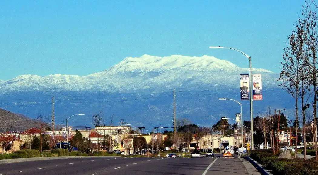 Snow-capped Mount San Jacinto rising above a commercial street in Menifee, California
